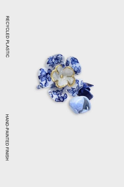 Handcrafted flower ring made from recycled plastic, featuring blue-and-white porcelain-inspired floral patterns with hand-painted gold detailing.