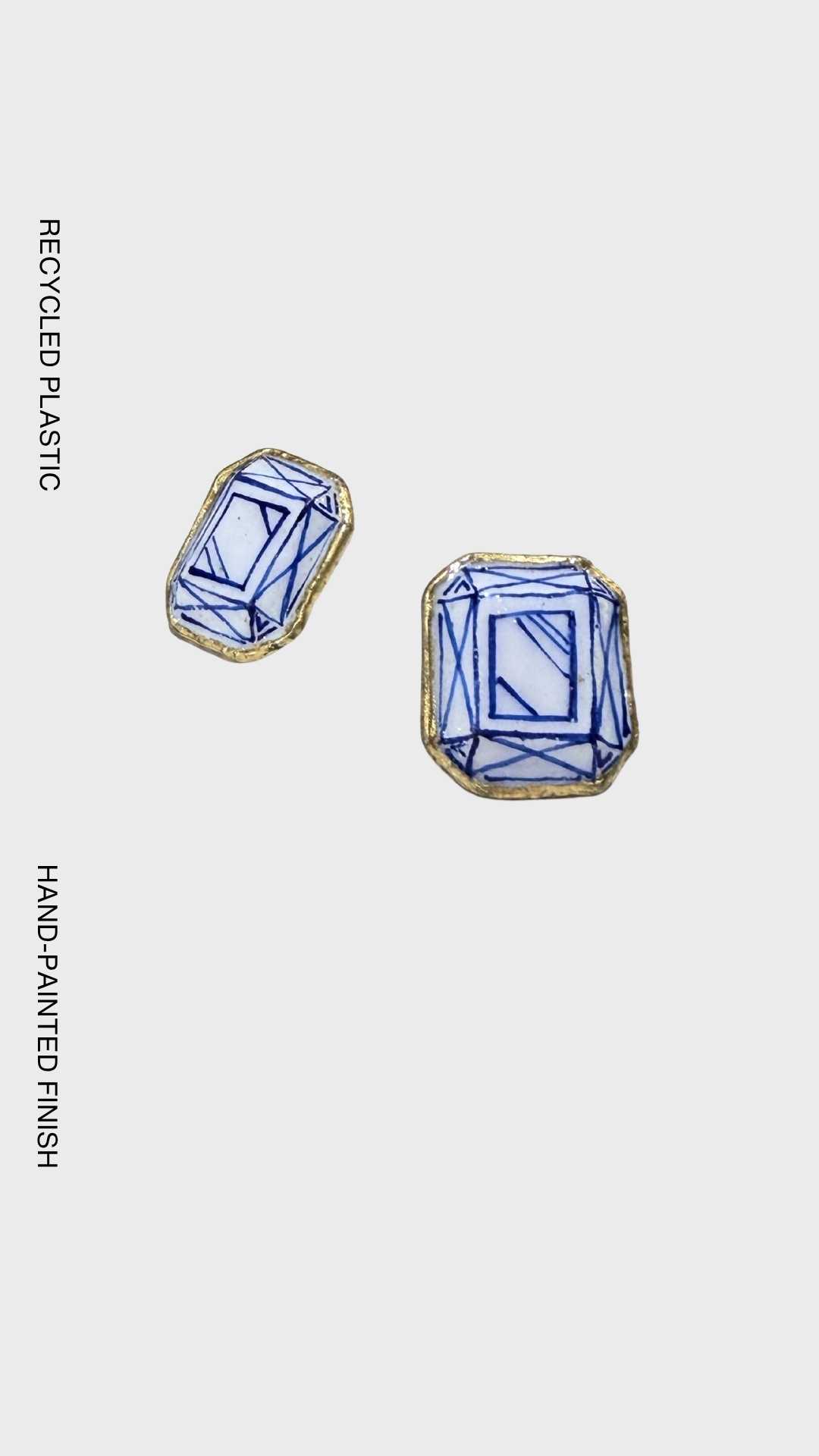 Handcrafted geometric earrings made from recycled plastic, inspired by diamond-cut facets with hand-painted blue detailing and gold edging.
