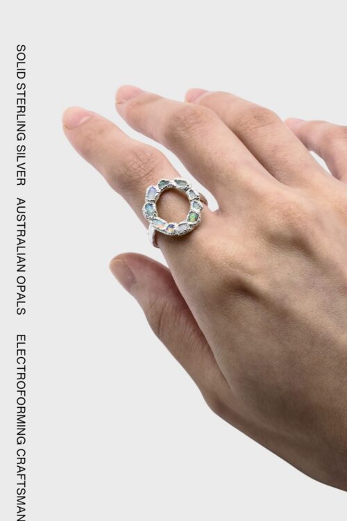 Australian opal circle ring featuring multicoloured opals in an organic textured silver setting, worn on the hand.